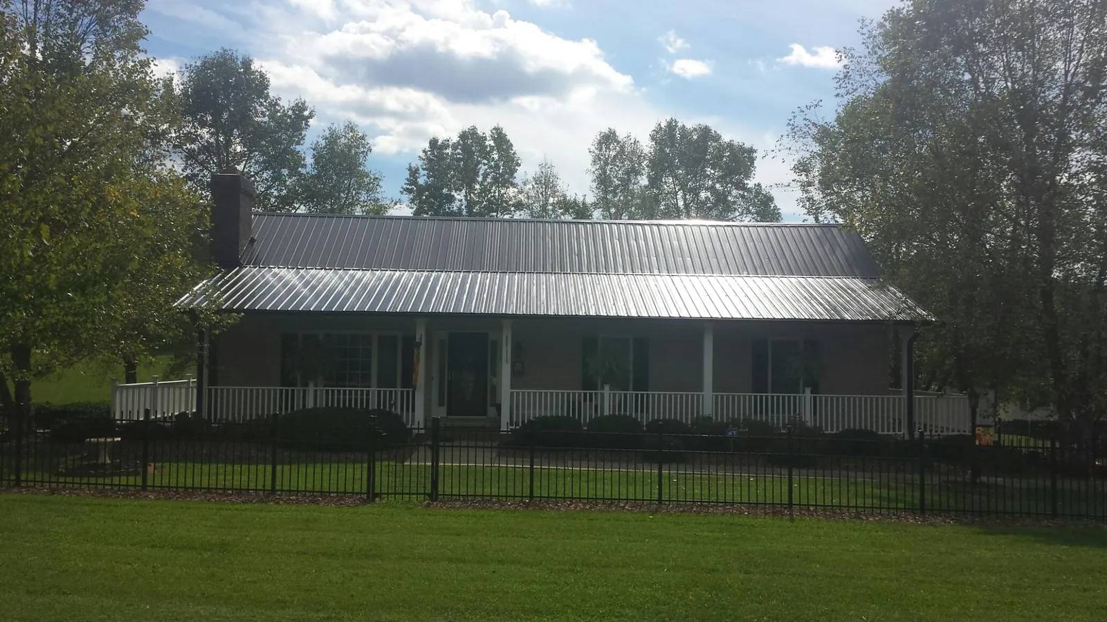 Gray metal roof on a brick ranch with a full width front porch — Gutter Guard Installation work by our crew in Portage