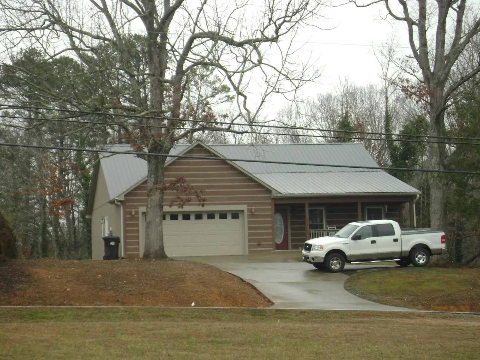 Gray metal roof on a log sided house with an attached two car garage in Portage